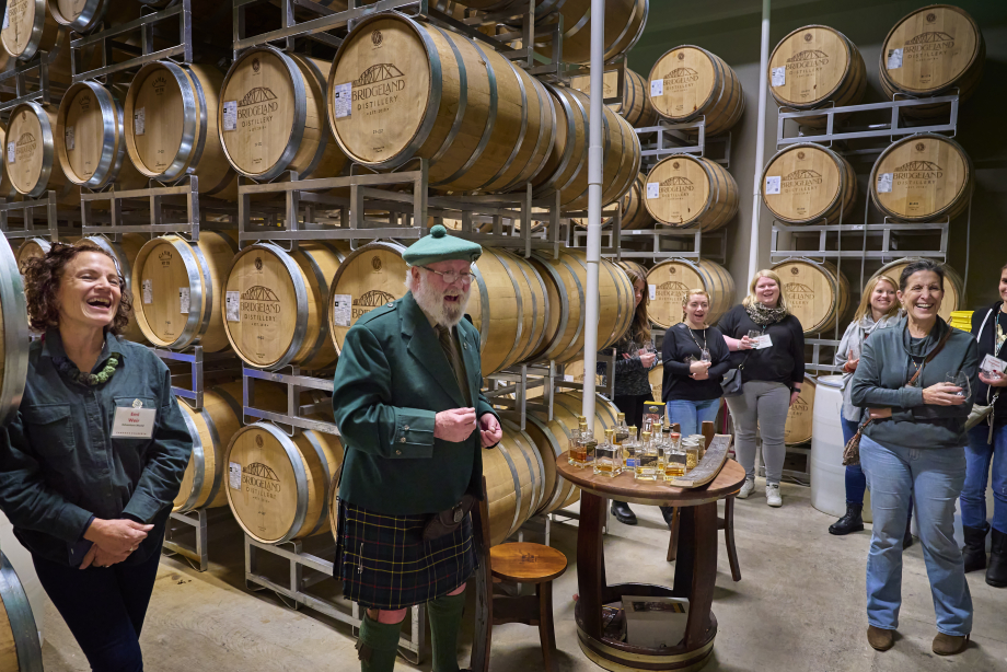 Man dressed in a kilt hosting a whiskey tasting in the barrel room of a distillery